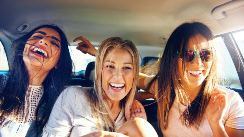 photo of authentic women laughing in a car