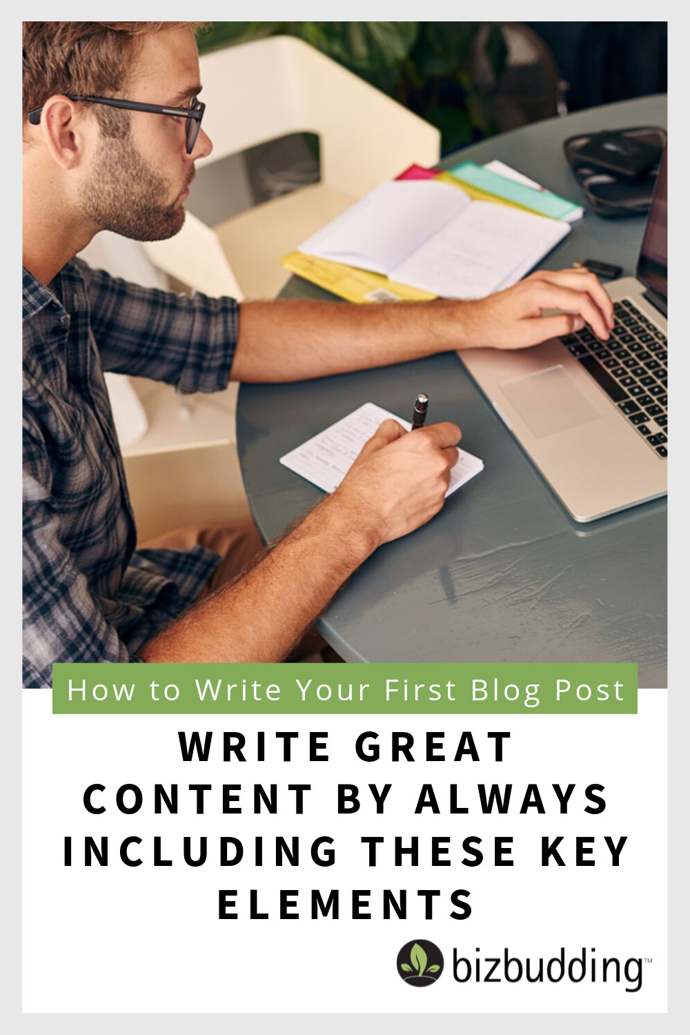 Man writing in a notebook while staring at a laptop.