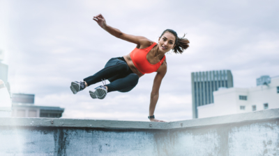 Young athletic woman jumping over wall