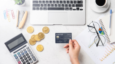 photo of hand holding credit card next to coins and laptop representing ecommerce website