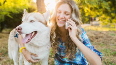 photo of woman and her dog at park while she talks on phone