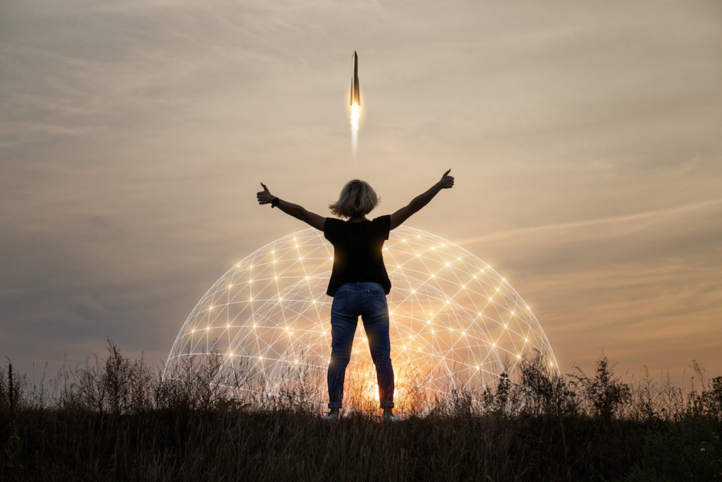 photo of woman standing in front of a rocket lifting off