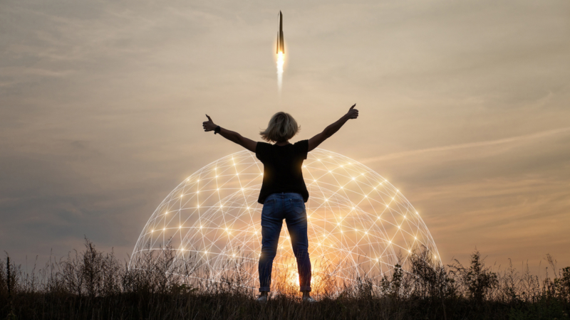 photo of woman standing in front of a rocket lifting off