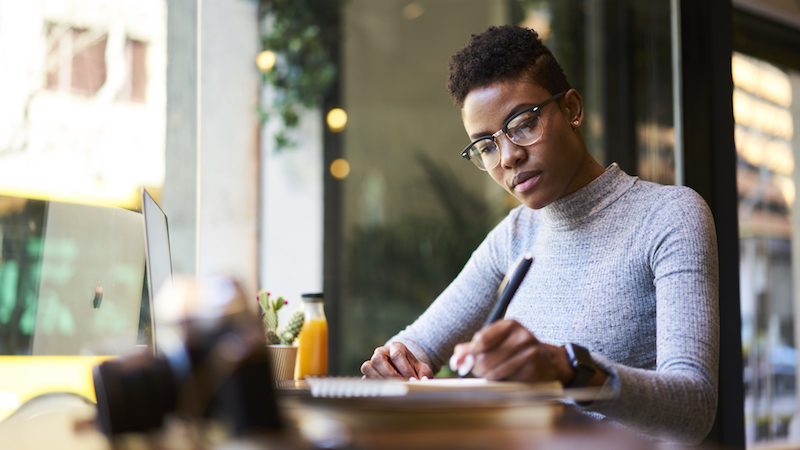 Woman sitting at desk writing in notebook