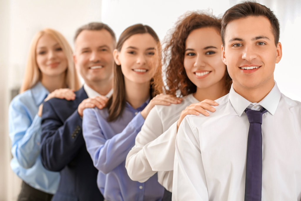 Portrait of business people in office with hands on each other's shoulders