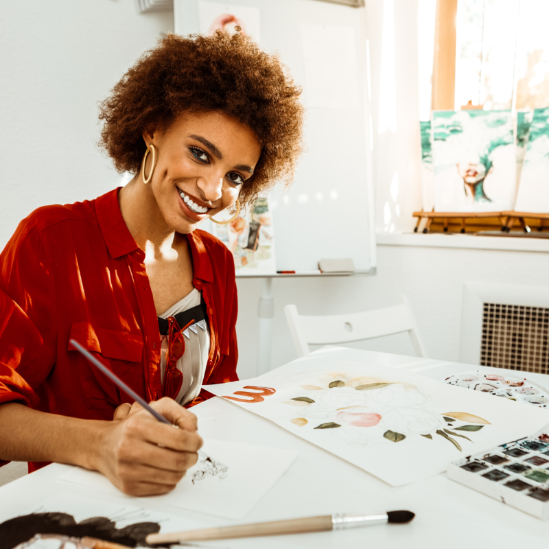 Beautiful young artist smiling and looking at camera while drawing