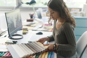 Professional decorator working in her studio, she is choosing fabric swatches for her project