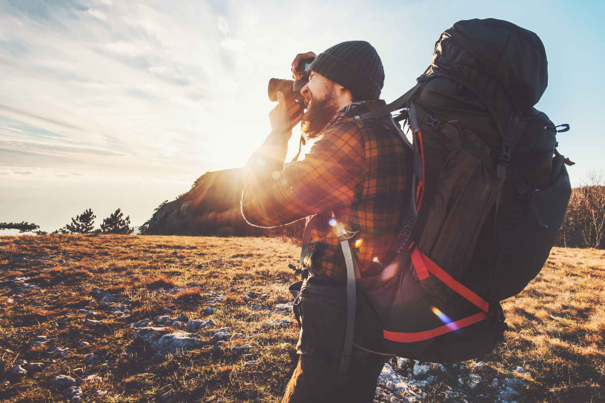 Male photographer with backpack and camera taking photos in nature