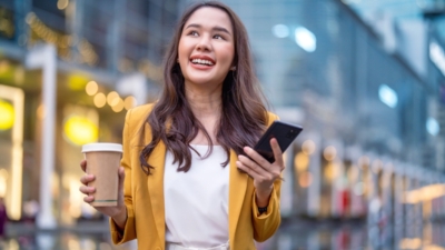Urban modern lifestyle fashion portrait of asian young female stylish casual walking with coffee cup and smartphone connection on the street, wearing cute trendy outfit 