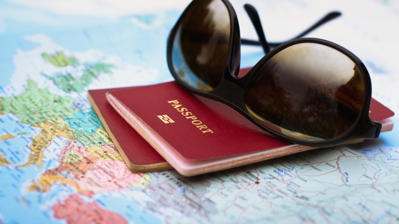 sunglasses and passports stacked on top of an open map; travel concept