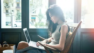 photo of a young woman writing her first blog post by a sunny window