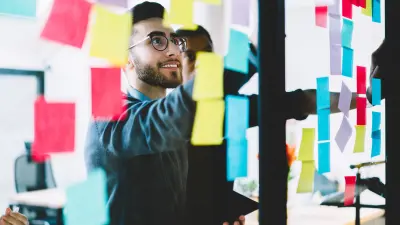 Marketer looking at colorful sticky notes on glass wall
