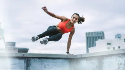 Young athletic woman jumping over wall