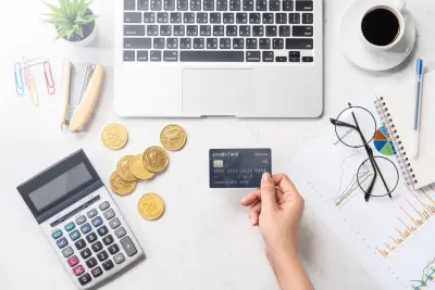 photo of hand holding credit card next to coins and laptop representing ecommerce website