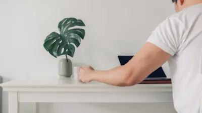 minimalist photo of a person sitting at a white desk with green plant