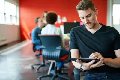 Confident male designer working on a digital tablet in red creative office space