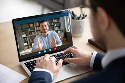 Back View Of Businessman Talking With Male Business Partner On Online Video Call
