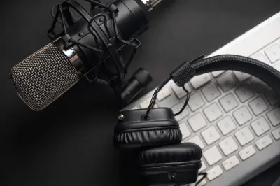 Microphone for podcasts and studio headphones on a PC keyboard on a black background, horizontal frame