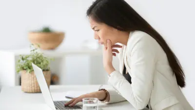 Puzzled confused asian woman thinking hard concerned about online problem solution looking at laptop screen, worried serious korean businesswoman focused on solving difficult work computer task