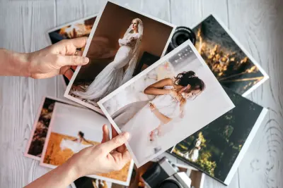 Person holding two printed photos of brides over stack of other wedding photos