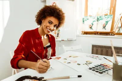 Beautiful young artist smiling and looking at camera while drawing