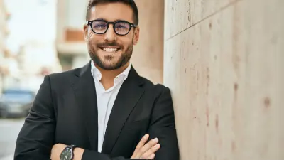 Young hispanic businessman with arms crossed smiling happy at the city.