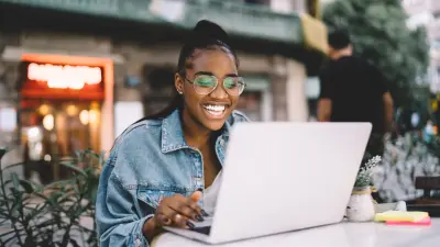happy blogger on laptop at outdoor cafe