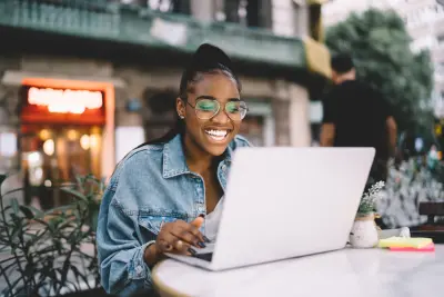 happy blogger on laptop at outdoor cafe