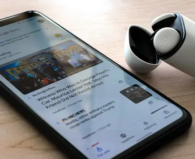 A Google Pixel 4 XL displays news of the Nationwide Protests while resting next to a pair of ear buds