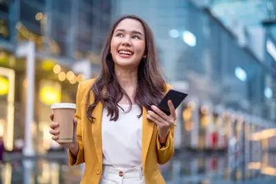 Urban modern lifestyle fashion portrait of asian young female stylish casual walking with coffee cup and smartphone connection on the street, wearing cute trendy outfit 