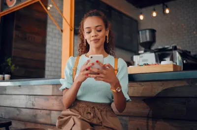 Phone, social media and coffee shop with a woman typing a text message while sitting in a cafe to relax. 