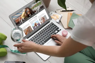 Female lifestyle blogger with glass of water and laptop on light wooden floor
