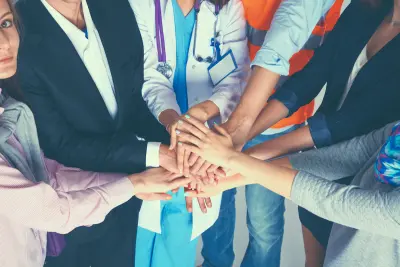 Portrait of people with various occupations putting their hands on top each other; community concept