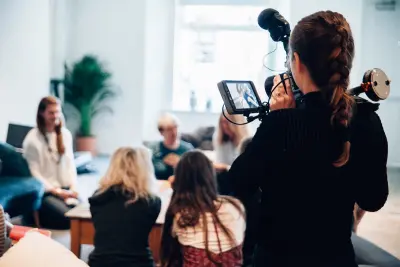 woman holding camera filming a room of people