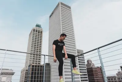 man sitting on guard rail with city skyline in background