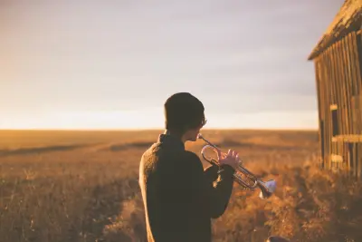 man playing trumpet outside house on field during daytime
