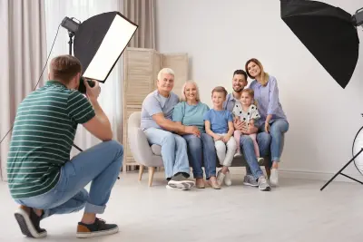 Professional photographer taking photo of family on sofa in studio
