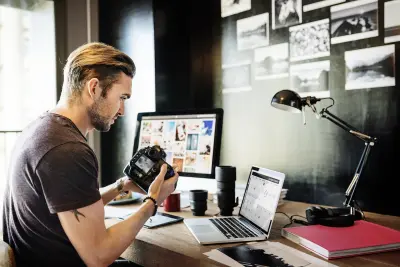 photographer sitting at computer desk holding camera