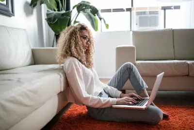 blogger writing on laptop sitting on floor 